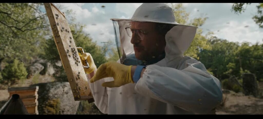 A man in a bee suit posing for an Apple Watch Series 9 advert holding a bee hive.