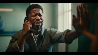 A man talking on a cell phone in a room during the Chicken Licken ad.