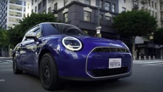 A electrifying blue MINI is grooving down a city street.