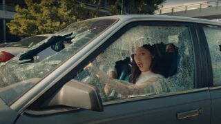 A woman is sitting in a shattered car.