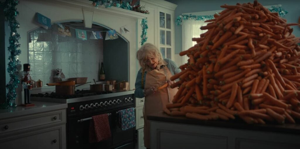 An ALDI Australia advertisement featuring a woman standing in front of a large pile of carrots for Christmas 2023.
