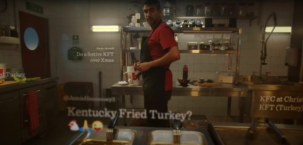 A man is standing in a kitchen with a KFC turkey.