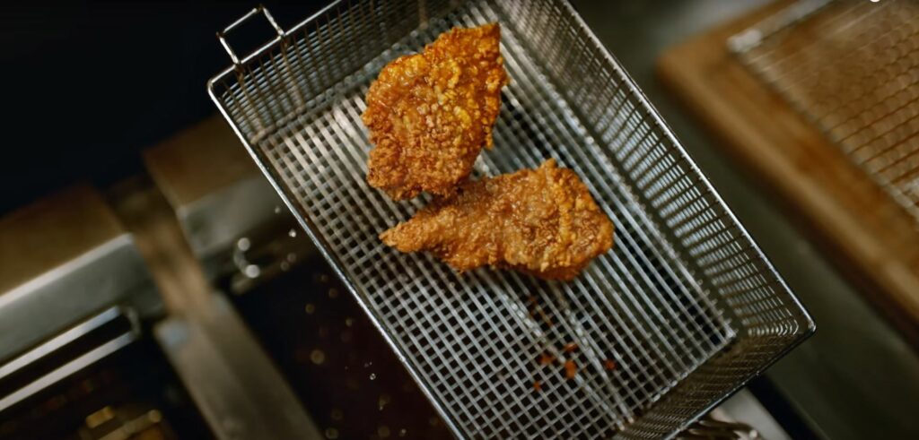 Embracing the crispy goodness of KFC's fried chicken in a metal basket.