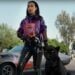 A woman in leather pants and a purple jacket stands next to a black panther and a vintage car, holding a bag of Doritos. Trees and a parking lot are in the background. Don't miss the bold style featured in Ads 2024, where you can truly meat your flavor with Jack Link's.