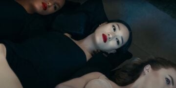 Three people lie close together, wearing dark clothing and bold lipstick, looking upward in a striking Dolce & Gabbana advert.
