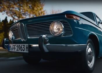 A classic blue car with round headlights and a chrome grille is parked on the street, as if plucked from a BMW Christmas ad. The license plate reads "MFF 1963 H," making it seem like the perfect nostalgic gift under the festive lights.