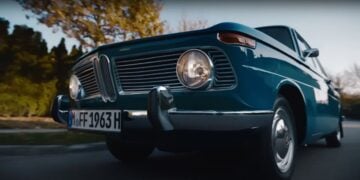 A classic blue car with round headlights and a chrome grille is parked on the street, as if plucked from a BMW Christmas ad. The license plate reads "MFF 1963 H," making it seem like the perfect nostalgic gift under the festive lights.