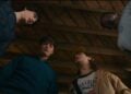 Four young people stand in a circle looking downward under a wooden ceiling, viewed from a low angle, reminiscent of a scene from Stranger Things Reunion on MagentaTV.